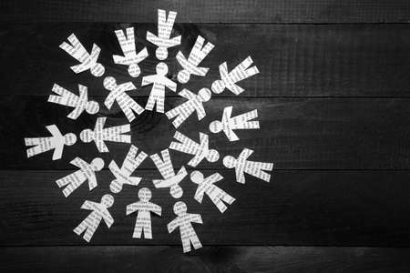 Clipped paper doll with Greek text on wooden black background in a circleの写真素材