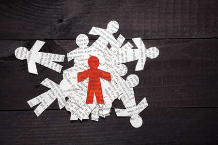 Clipped paper doll with Greek text on wooden black background. Stands out the red oneの写真素材