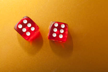 Two red dice on golden background with space for textの写真素材