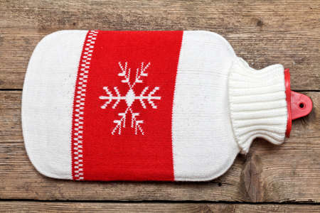 Hot water bottle or bag on wooden background