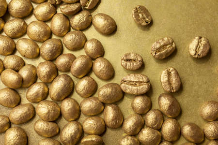 Golden beans of coffee on golden surfaceの写真素材