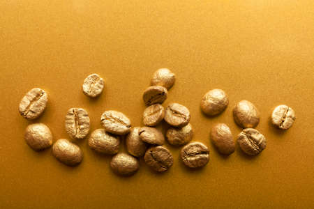 Golden beans of coffee on golden surfaceの写真素材