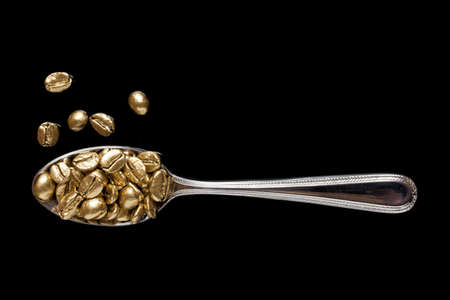 Coffee beans in a spoon on a black surfaceの写真素材