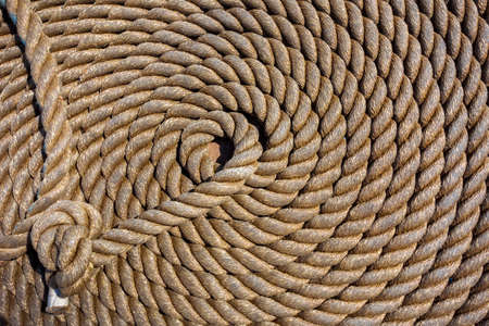 Thick rope in spiral or ring shape on a wooden sailing ship floorの写真素材
