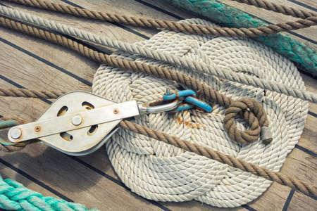Rope braided in celtic knot work shape on a wooden sailing ship floor with steel pulleyの写真素材