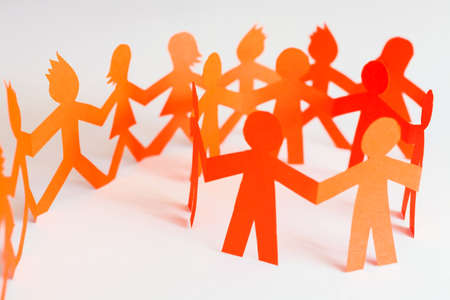 Group of paper doll holding hands. Teamwork concept paper craft. Orange dolls on white background

の写真素材
