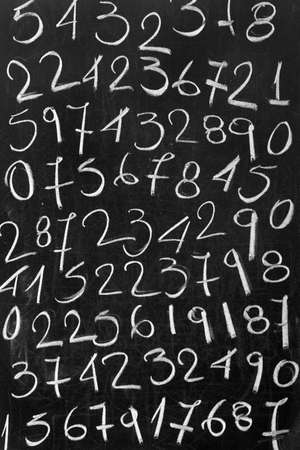 Numbers handwritten with white chalk on a blackboard. Abstract mathematics background