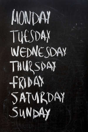 Conceptual weekdays list written on black chalkboard blackboard. Monday Tuesday Wednesday Thursday...