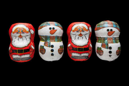 Chocolates with Santa Claus and a snowman isolated on black background の写真素材