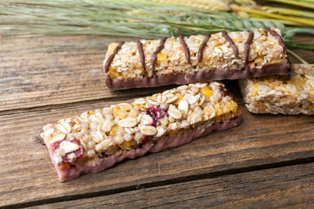 Cereal bars and dry wheat on a wooden tableの写真素材