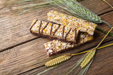 Cereal bars and dry wheat on a wooden tableの写真素材