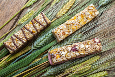 Cereal bars and dry wheat on a wooden tableの写真素材