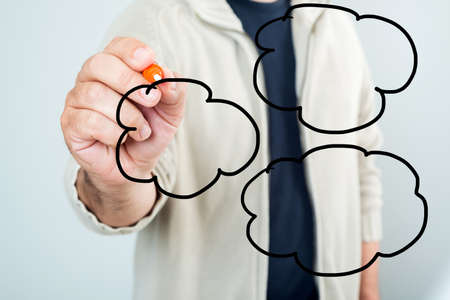 Young casual man planning clouds on glass board with marker の写真素材
