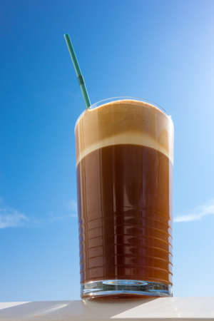 Frappe coffee in cup over a blue skyの写真素材