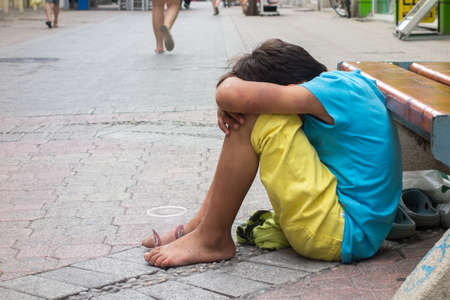 KOMOTINI, GREECE - JULY 5: Abused and unclean beggar child boy on the sidewalk on July 5, 2014 in...