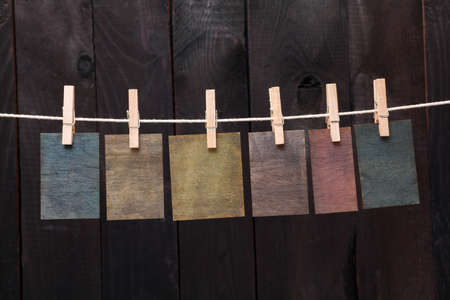 Close up of wooden notes attach to rope with clothes pins on dark wooden background 