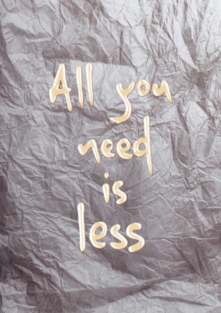 ALL YOU NEED IS LESS quote on a crumpled piece of paper background の写真素材