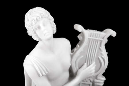 Statue of Orpheus holding a lyre in an ancient Greek style on black backgroundの写真素材