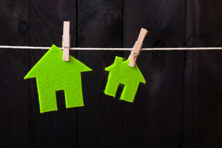Green eco houses attach to rope with clothes pins on dark wooden backgroundの写真素材