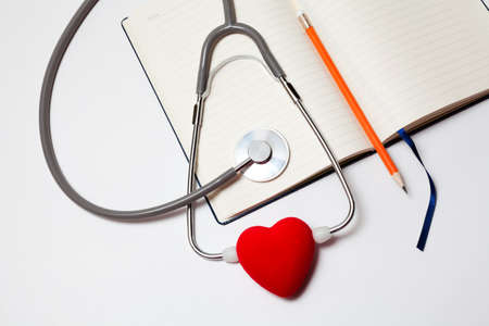 Blank clipboard with stethoscope, heart and space for messages on white backgroundの写真素材