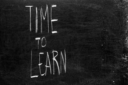 Written time to learn on the blackboard with white chalkの写真素材