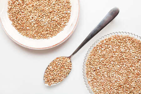 Îuckwheat groats in a dish with metallic spoonの写真素材