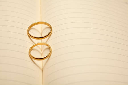 Wedding rings forming a heart onto a notebookの写真素材