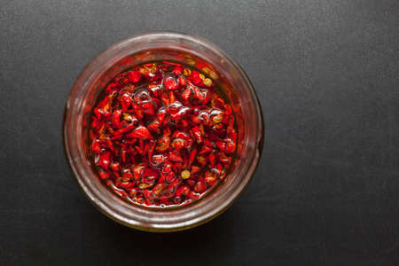 Red hot Trinidad moruga scorpion peppers chopped in olive oil on black backgroundの写真素材