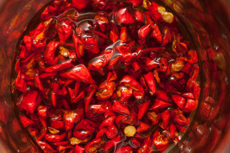 Red hot Trinidad moruga scorpion peppers chopped in olive oil on black backgroundの写真素材