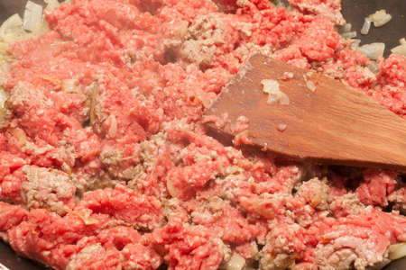 Raw minced meat in the pan with wooden spoonの写真素材