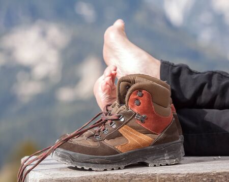 Barefoot person relaxing on a bench in the mountains