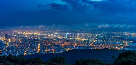 Panoramic view of Da Nang at night from Ban Co Peak, featuring sparkling city lights, high-rise buildings, illuminated bridges over the Han River, and vibrant streets.の写真素材