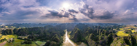 A stunning aerial view of the Ngo Dong River winding through limestone mountains and golden rice...