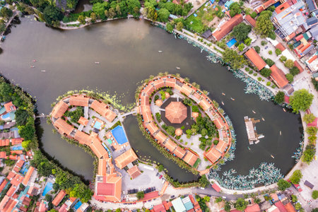 A stunning aerial view of the Ngo Dong River winding through limestone mountains and golden rice fields in Tam Coc, Vietnam.の写真素材