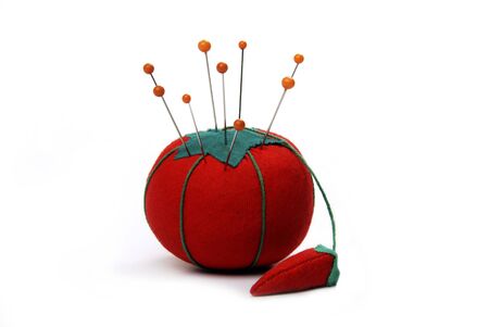 Orange pins stuck into a pin cushion in the shape of a tomatoの写真素材