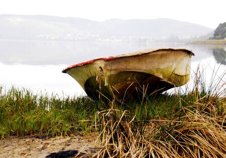 A lonely row boat moored on a grassy bankの写真素材
