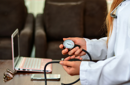 Cropped image of Female doctor checking blood pressure of patient at table