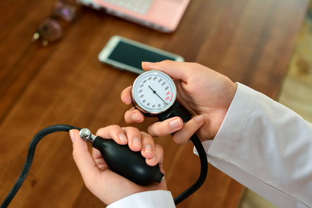 Cropped image of Female doctor checking blood pressure of patient at tableの写真素材