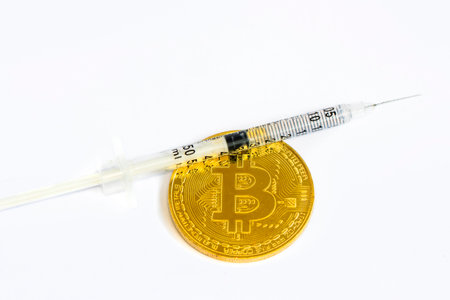 Bitcoin coin and syringe on white background. Cryptocurrency concept.の写真素材