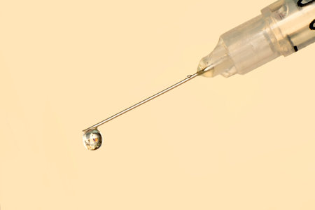 Syringe with a drop on a beige background. close-up.の写真素材
