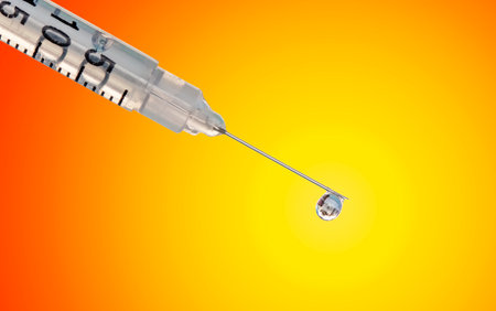 Close-up of syringe and drop of vaccine on orange background