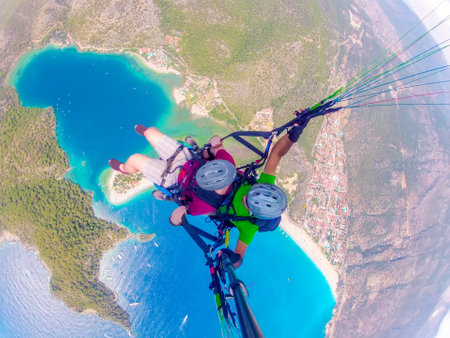 Paraglider tandem flying over the sea with blue water and mountains in bright sunny day. Aerial view of paraglider and Blue Lagoon in Oludeniz, Turkey. extreme sport. landscapeの写真素材