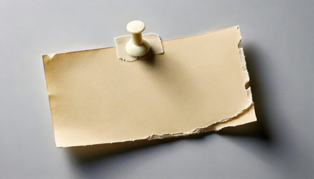 Torn piece of paper with a pin on a gray background.の素材