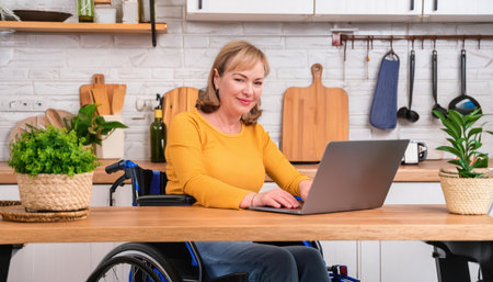 Smiling disabled woman in wheelchair using laptop at home. Online shopping concept.の素材