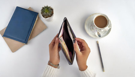 Female hands holding a wallet and a cup of coffee on a white backgroundの素材