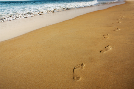 footsteps on the sand near the ocean waveの写真素材