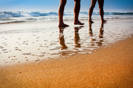 photo of legs of two people walking on the beach in the sunset unfocusedの写真素材