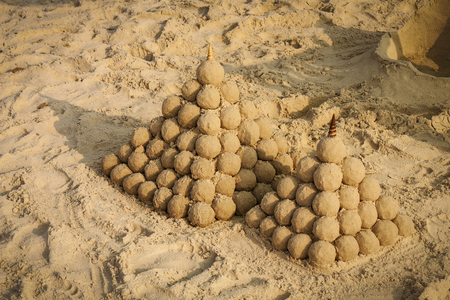 two pyramidal sandcastles on the beach in the sunsetの写真素材