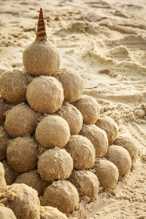 pyramidal sandcastle with cone seashell on the topの写真素材