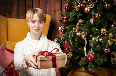 Beautiful woman wearing a warm sweater and socks, sitting on the floor near the Christmas treeの写真素材